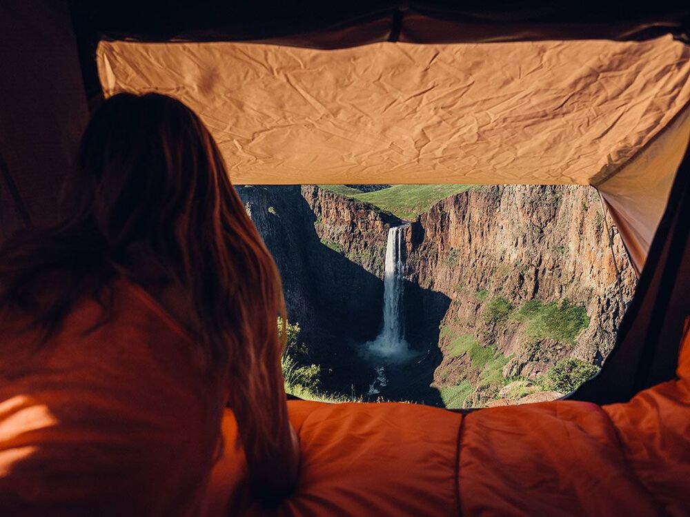 A Person Laying Inside The Front Runner Roof Top Tent Watching A Waterfall